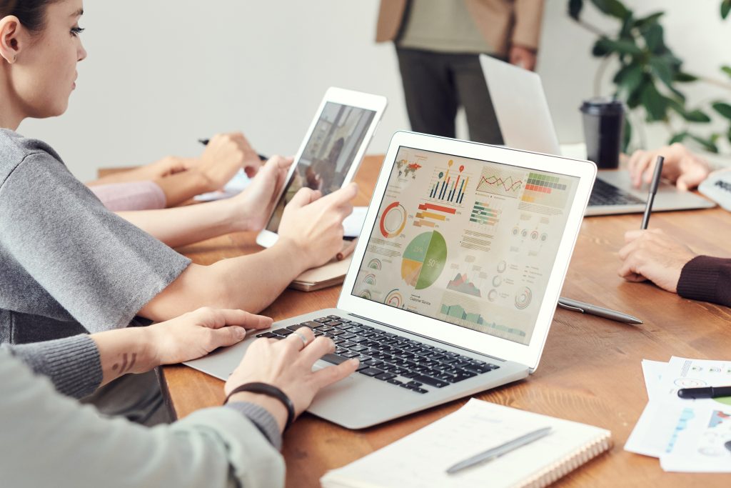 Menschen sitzen am Tisch mit verschiedenen Laptops
